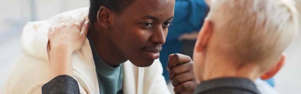 High angle view at young African-American man smiling gratefully to psychologist while while in support group circle, copy space